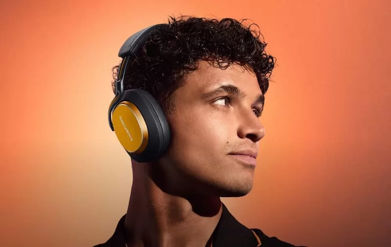 Homme portant des écouteurs modernes, fond orange.